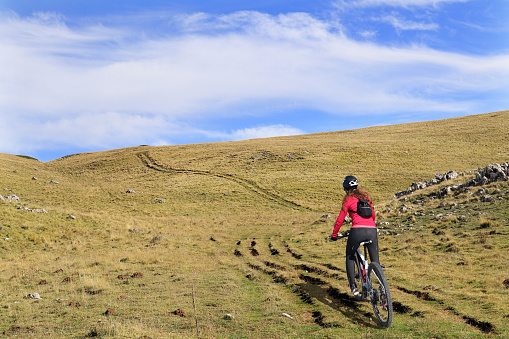 A woman riding an e-bike on a track at Monte Incappucciata, on the Appennini of the Abruzzo region, in Italy