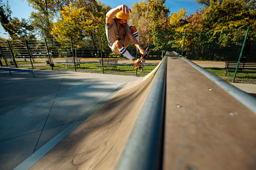 A young skater is jumping on the spine ramp in the skatepark.