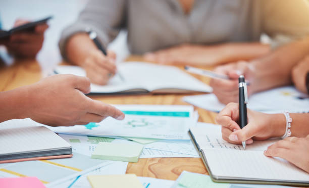 istock Target audience, research and hands with marketing paper, notebook and post it sticky note on office desk or table. Closeup teamwork, collaboration and brand strategy while writing media advertising 1445268784