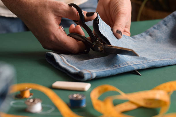 istock Seamstress using scissors to cut jeans for hemming 1445271615