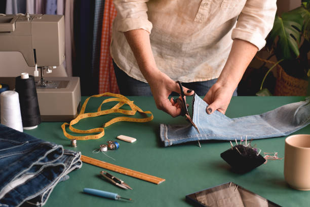 istock Seamstress using scissors to cut jeans for hemming 1445271616