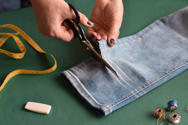 istock Seamstress using scissors to cut jeans for hemming 1445271617
