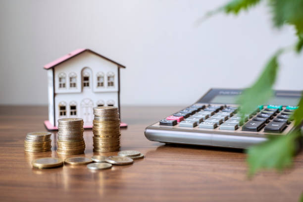 calculatrice avec maison en bois et pile de pièces sur table en bois. investissement immobilier et concept financier d’hypothèque immobilière - small built structure office business photos et images de collection