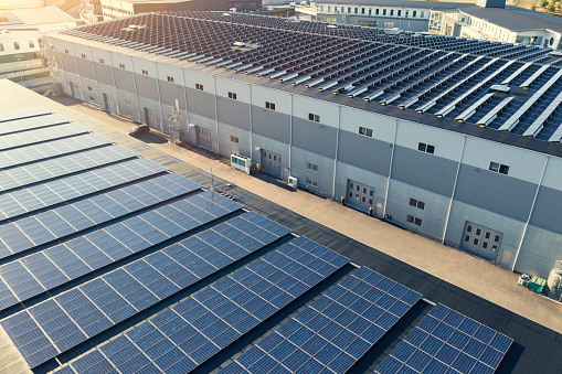 A modern industrial district with solar power installations on the rooftops of the buildings.