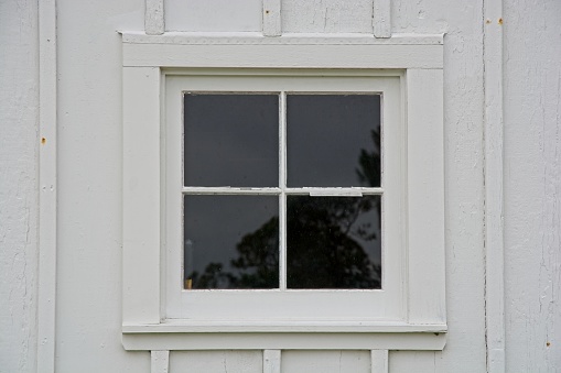 Window panes in weathered white board and batten wall siding