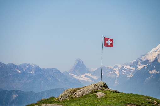 A swiss flag with view on the Matterhorn in the distance