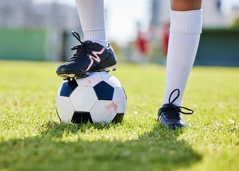 Soccer, ball and shoes of athlete on grass for training practice in fitness, sports and health. Motivation, exercise and workout with soccer player on football field for goals, wellness and games