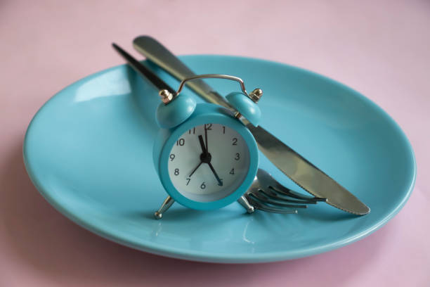 Intermittent Fasting for Busy Professionals 2 alarm clock plate fork knife on a colored background