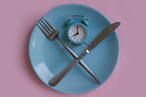 istock Alarm clock, plate, fork knife on a colored background 1445281779