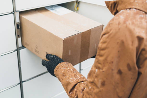 istock A man with a box in his hands near the self-service mail terminal. Parcel delivery machine. Person holding a cardboard box. Mail delivery and post service, online shopping, e commerce concept 1445291739