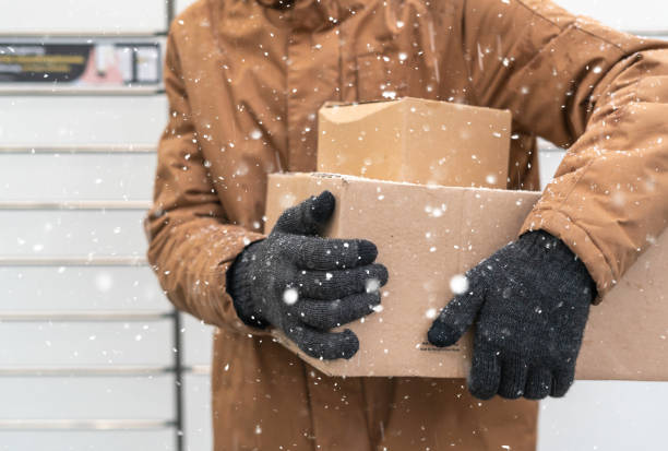 istock A man with a box in his hands near the self-service mail terminal. Parcel delivery machine. Person holding a cardboard box. Mail delivery and post service, online shopping, e commerce concept 1445291743
