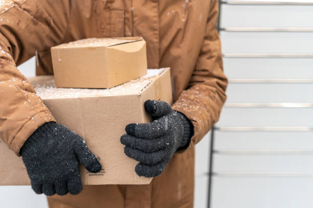 istock A man with a box in his hands near the self-service mail terminal. Parcel delivery machine. Person holding a cardboard box. Mail delivery and post service, online shopping, e commerce concept 1445291752