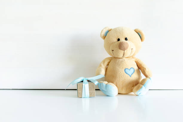 istock Little teddy bear toy with gift box on white table background with copy space. Baby shower, present for boy child birthday 1445295378