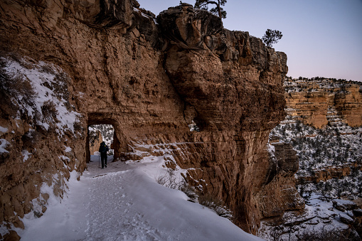 Female hiker admiring Bryce national park in winter with light snow and hoodos all around in Utah, United States