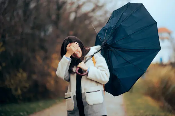 Photo of Woman with Broken Umbrella Walking in a Storm