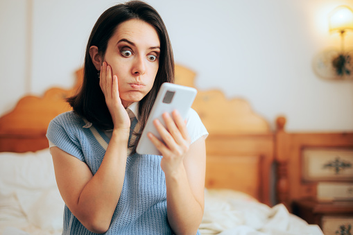 Mujer divertida en estado de shock leyendo un mensaje de texto en su teléfono photo
