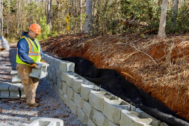 istock Contractor installing concrete block wall as part of retaining wall construction that is being built as part of the project 1445316372