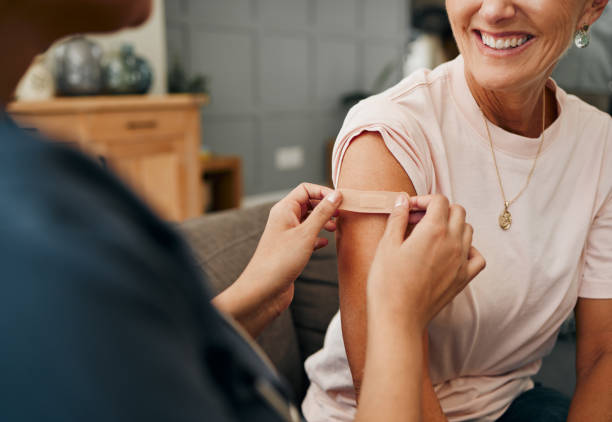 woman, smile and plaster after injection for vaccine against covid. happy, senior and lady vaccination for coronavirus on sofa in doctor office for health, wellness and safety from global pandemic - injecting flu virus cold and flu doctors office imagens e fotografias de stock