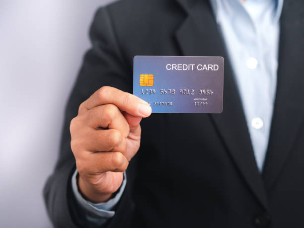 istock Businessman holding a mockup blue credit card while standing in a studio 1445323320