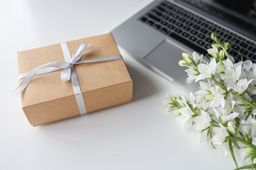 Cardboard gift box with a bow and flowers on a white background