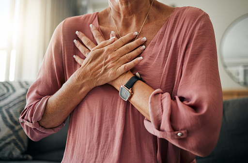 Senior woman, hands or chest pain in heart attack, anxiety or panic in house or home living room. Zoom, stroke or cardiovascular emergency for sick retirement elderly or stress person in medical risk