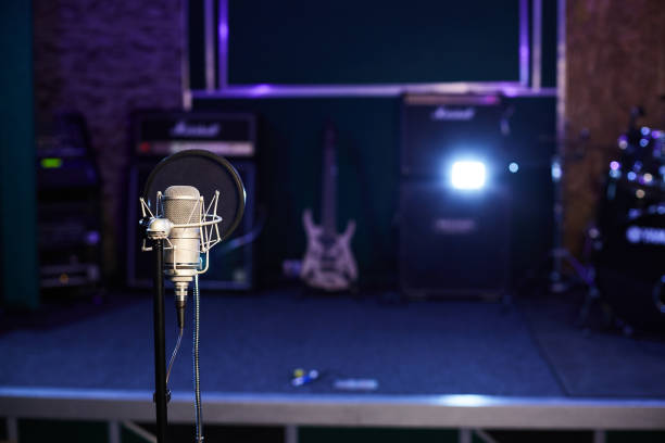 istock Microphone with a pop shield closeup on the background of a stage. Microphone stand with a condenser for records vocals, speakers and sound of musical instrument. 1445324689