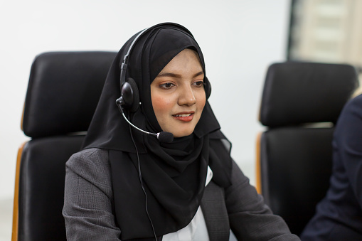 Asian muslim woman customer support operator with headset. Muslim female wearing hijab headscarf working with headset in office. Contact center and customer service concept