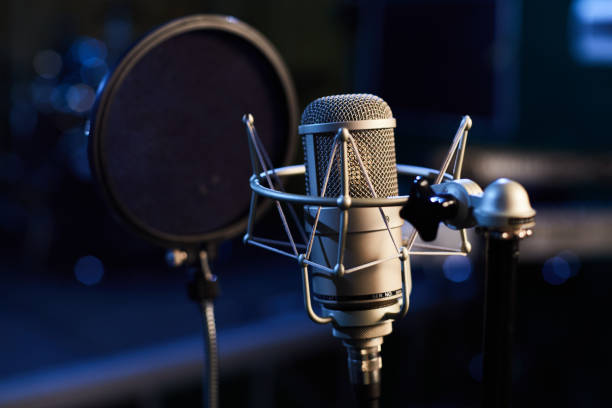 istock Microphone with a pop shield closeup on the background of a professional recording studio. Microphone stand with a condenser for records vocals, speakers and sound of musical instrument. 1445324912