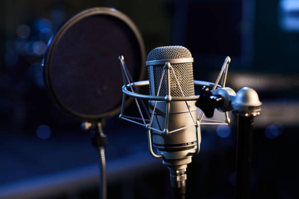 Microphone with a pop shield closeup on the background of a professional recording studio. Microphone stand with a condenser for records vocals, speakers and sound of musical instrument. stock photo
