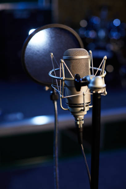 istock Microphone with a pop shield closeup on the background of a professional recording studio. Microphone stand with a condenser for records vocals, speakers and sound of musical instrument. 1445324928