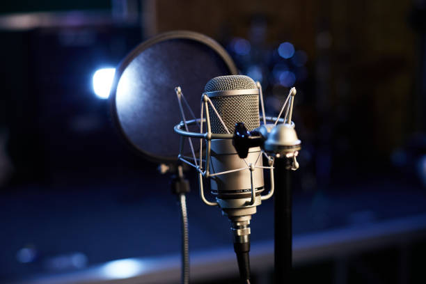 istock Microphone with a pop shield closeup on the background of a professional recording studio. Microphone stand with a condenser for records vocals, speakers and sound of musical instrument. 1445325449