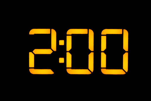 Electronic digital clock with yellow numbers on a black background shows the time two zero zero nights. Isolate, close-up.
