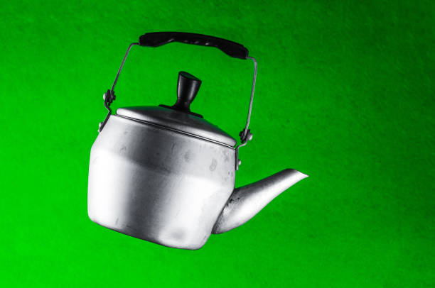 Levitating aluminum kettle of small capacity on a green background