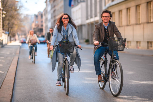 riding bicycles to work lead to a healthy lifestyle - action mature adult bicycle senior couple imagens e fotografias de stock
