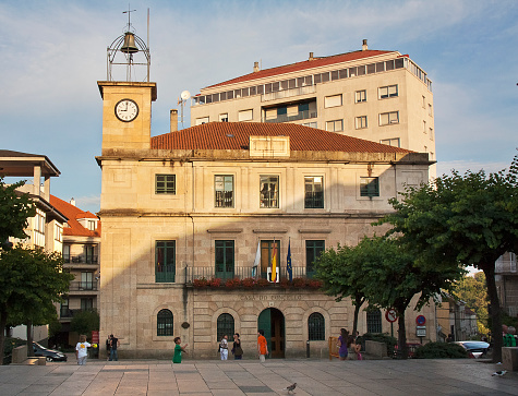 Carballino, Spain-July 7,2011: Town Hall in O Carballiño, Ourense province, Galicia, Spain. Clock and bell  tower, clear blue sky at dusk.