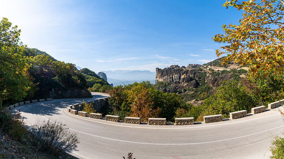 A winding mountain road in with rock formations and autumn foliage forest colors