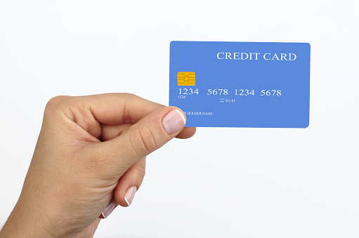 A close-up woman's hand holds a blue  credit card isolated on white background.