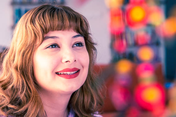 Portrait of a young woman posing with a friendly smile at her home one evening.