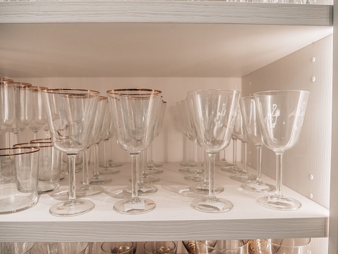 A group of glasses on a shelf in the kitchen cabinet