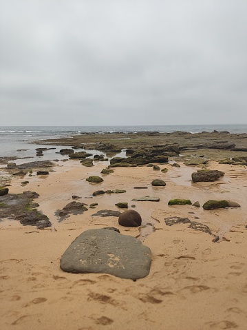 A vertical shot of the Praia do Canical beach in Portugal with rocks and a cloudscape