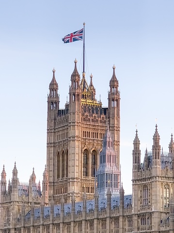 A vertical shot of the Palace of Westminster with the UK flag in London