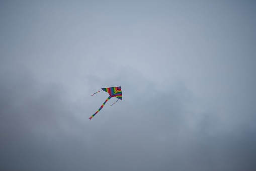 A low angle shot of a colorful kite flying in the cloudy sky