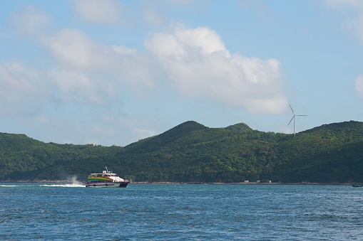 A wind turbine behind the water with a sailing boat in Lamma Island, Hong Kong