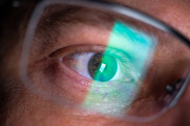 Irritated eyes of a person wearing glasses due to work on screens smartphone display is reflected in a man's glasses - part of a series german iris stock pictures, royalty-free photos & images