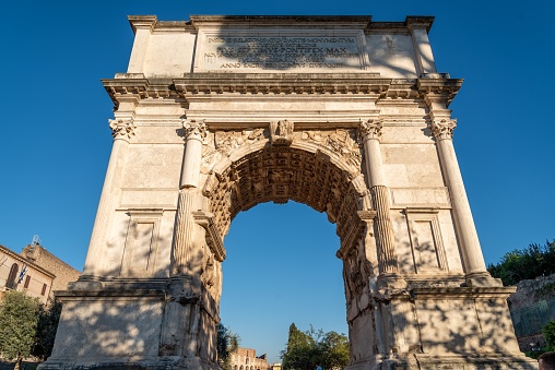 A low-angle shot of the Arch of Titus in Rome with a blue sky in the background