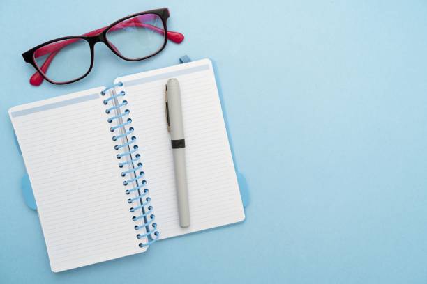 istock Top view of a notepad, glasses and a pen isolated on a white table 1445352770