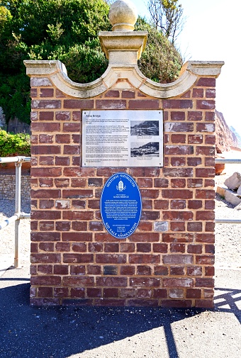 Brick wall with an information sign about the Alma Bridge, Sidmouth, Devon, UK, Europe.