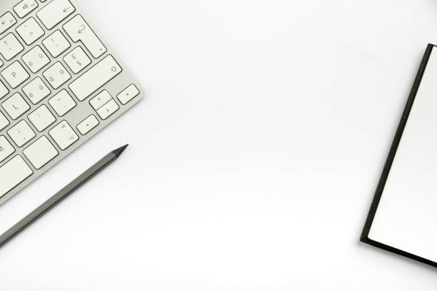 A notepad, pencil, and a part of a white computer keyboard isolated on a white background