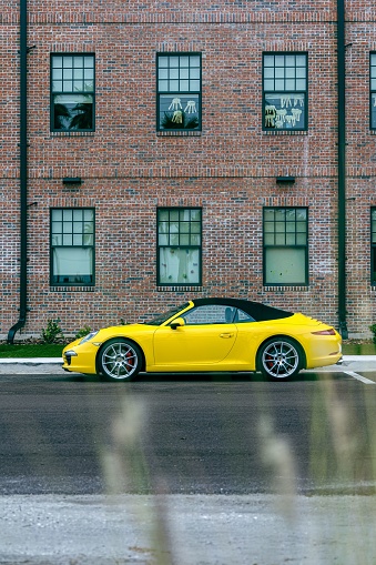 Saint Petersburg, United States – June 05, 2022: A vertical side view of a modern yellow Porsche 911 GT3 sportscar parked on the road