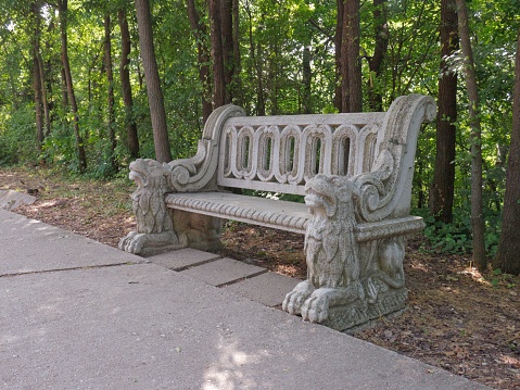 A white bench with lion sculptures in the public park